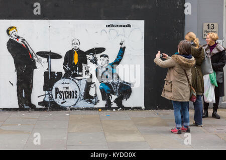 Shoreditch, London, 14. Jan 2018. Londonern und Touristen Reagieren und Interagieren mit einem neuen street art Stück für Loretto, Darstellung von US-Präsident Donald Trump als Leadsänger der Band "Psychos", mit Wladimir Putin am Schlagzeug und Nordkoreas Kim Jong-un an der Gitarre. Die Arbeit ist von der Londoner Künstler Loretto, deren Stücke mit sozialpolitischen Kontext, in banksy-esque Stil, über London im letzten Jahr erschienen sind. Credit: Imageplotter Nachrichten und Sport/Alamy leben Nachrichten Stockfoto