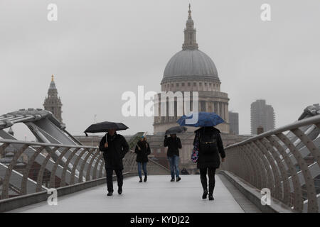 London, Großbritannien. 15 Jan, 2018. Menschen mit Schirmen über die Millennium Bridge in London bei regnerischem Wetter heute. Credit: London pix/Alamy leben Nachrichten Stockfoto