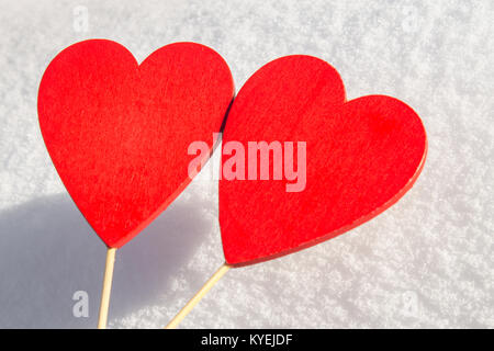 Im Schnee liegt ein rotes Herz aus Holz. Vorlage für eine Weihnachtskarte mit einem weißen Textur und freien Platz für Text Stockfoto