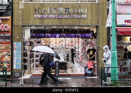 Ein Mann mit einem Regenschirm Spaziergänge Vergangenheit einen Souvenirshop mit bunten Zeichen in der koreanischen Stadt Nachbarschaft von Shin-okubo Station, Tokyo, Japan an einem regnerischen Tag, 16. Oktober 2017. () Stockfoto