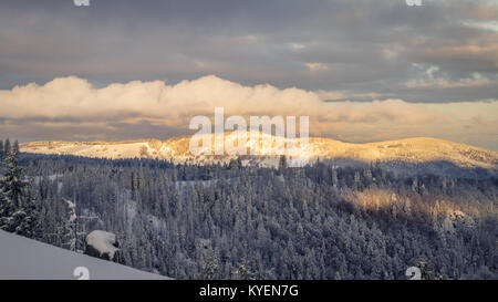 Am frühen Morgen Schnee Schauinsland im Schwarzwald in der Nähe Freiburg durch die Sonnenstrahlen erwärmt. Der Himmel öffnet sich und die Tannen sind Cov Stockfoto