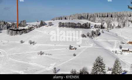 Die Skistation "todtnauberg" ist eines der Berühmtesten in den Schwarzwald. Aufhänger eines langsamen Aufzug vorbei mit der Bauernhäuser und Schnee Tanne abgedeckt Stockfoto