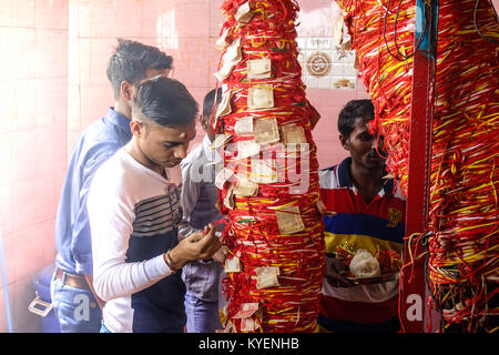 Ein junger Mann binden rot gefärbten Heiligen thread am Stamm des Baumes im Tempel, Haridwar, Indien Stockfoto