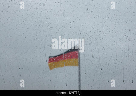 Deutsche Nationalflagge abgebildet durch Regentropfen auf das Glas von innen von der Kuppel des Reichstags in Berlin. Stockfoto