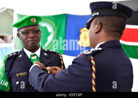 Assistant Inspector General der kenianischen Polizei (AIGP), Edward Mwamburi Pins eine Medaille auf eine Kenianische Polizisten, der seine Tour der Aufgabe im Rahmen der Mission der Afrikanischen Union in Somalia (AMISOM) abgeschlossen. Dies wurde bei einer Abschiedszeremonie in Mogadischu am 29. Dezember 2017. Die AMISOM Foto/Ilyas Ahmed Stockfoto