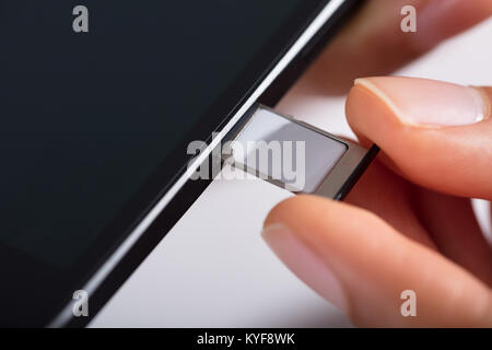 In der Nähe der Person Hand einfügen Micro-SIM-Karte im Handy Stockfoto