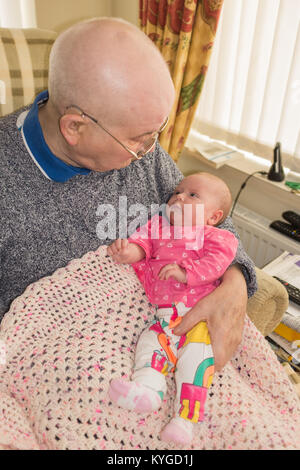 New Born Baby auf den Schoß von ihrem Urgroßvater, sah ihn an Stockfoto
