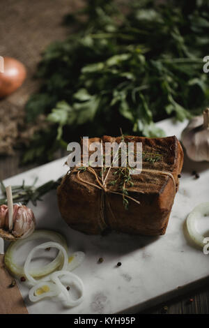 Klumpen von gesalzenem geräucherten Speck in Gaze mit einem Seil. Traditionelle russische und ukrainische Mahlzeit. Gesundes Essen mit pranami Gewürze, Kräuter, Zwiebel und Knoblauch. Stockfoto