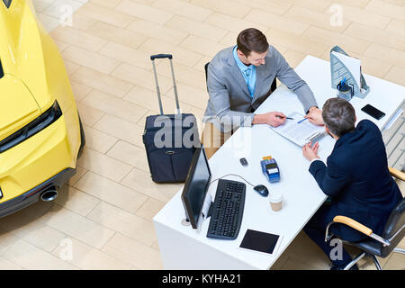 Oben Ansicht von stattlicher Mann lesen Mietvertrag am Schreibtisch sitzen im Händler Shop vermietung Luxus Auto für Business Reisen, Kopie Raum Stockfoto