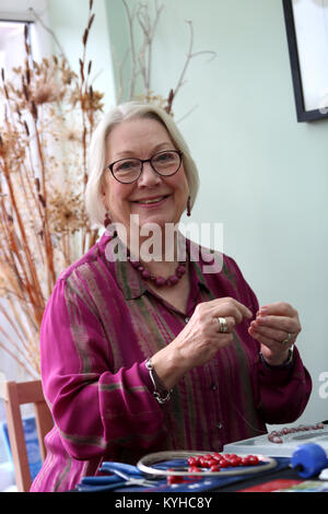 Eine Frau, die ein Halsband mit einer Halskette, Kit in Ihrem Haus in Sussex, UK. Stockfoto