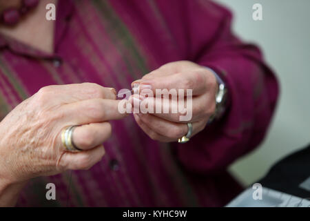 Eine Frau, die ein Halsband mit einer Halskette, Kit in Ihrem Haus in Sussex, UK. Stockfoto