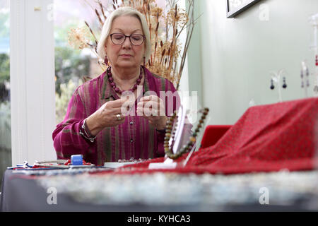 Eine Frau, die ein Halsband mit einer Halskette, Kit in Ihrem Haus in Sussex, UK. Stockfoto