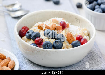 Haferflocken Haferflocken mit Heidelbeeren, Preiselbeeren und Mandeln in weiße Schüssel. Detailansicht. Konzept der gesunden Ernährung, Diäten, gesunden Lebensstil Stockfoto