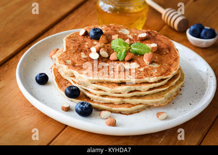 Glutenfreie Pfannkuchen mit Mandeln und Heidelbeeren auf weißem Schild auf hölzernen Tisch Stockfoto