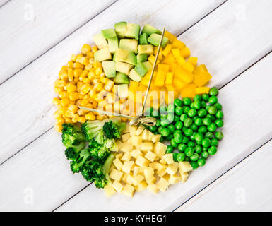 Uhr - vom grünen und gelben Gemüse auf einem weißen Hintergrund. top anzeigen. Konzept Stockfoto