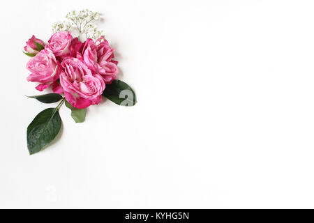 Dekoratives florale Komposition mit rosa Rosen, grüne Blätter und und Baby's Atem Gypsophila Blumen auf weißem Hintergrund. Flach, Ansicht von oben. Hochzeit oder Geburtstag gestaltete Foto. Stockfoto