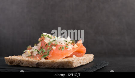 Geräucherter Lachs auf Toast mit Zwiebel und Petersilie Stockfoto