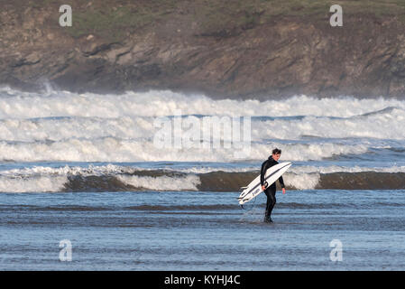 Polzeath surfen - ein müdes Surfer zu Fuß aus dem Meer auf Polzeath Strand an der Küste von North Cornwall. Stockfoto