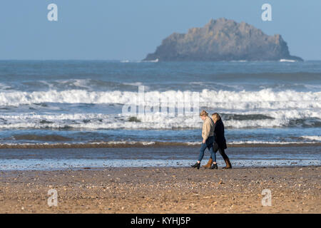 Polzeath - zwei Leute, die Frauen zu Fuß entlang der Küstenlinie auf Polzeath Strand an der Küste von North Cornwall. Stockfoto