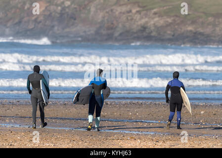 Polzeath Surfen - Drei Surfer ihre Surfbretter und gehen hinunter zum Meer auf Polzeath Strand an der Küste von North Cornwall. Stockfoto