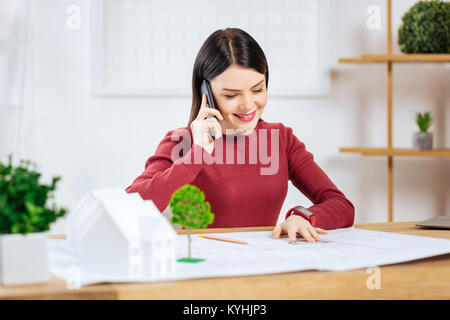 Freundliche junge Frau lächelnd, während Sie telefonieren Stockfoto