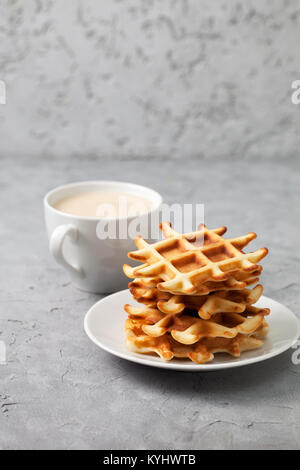 Stapel von Waffeln auf einem weissen Teller, Tasse Kaffee auf einem grauen konkreten Hintergrund Stockfoto