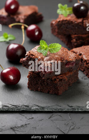 Stapel von Brownies mit Kirschen, frisch Kirsche auf schwarzen Stein Hintergrund closeup Stockfoto