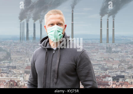 Nahaufnahme von einem Mann, der Mund Maske gegen Rauch ausstoßen von Fabrikschornsteinen Stockfoto