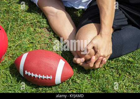 Nahaufnahme der männlichen Rugbyspieler Leiden Knieverletzung liegen auf Feld Stockfoto