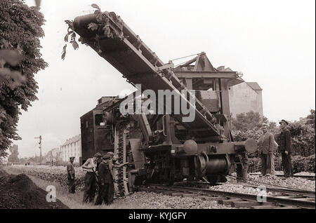 Foto mit einer Martis-Maschine, die zum Ausbreiten von Kies auf einem Eisenbahndamm in Maribor verwendet wurde, 1958, mit Industrie- und Verkehrsinfrastruktur. Stockfoto