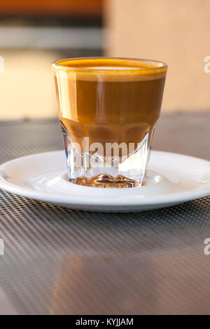 Seitenansicht der Cortado Kaffee in ein kleines Glas Keramik Untertasse auf metallischen Tabelle Stockfoto