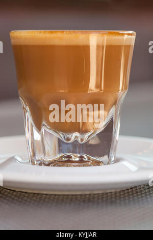 Seitenansicht der Cortado Kaffee in ein kleines Glas Keramik Untertasse auf metallischen Tabelle Stockfoto