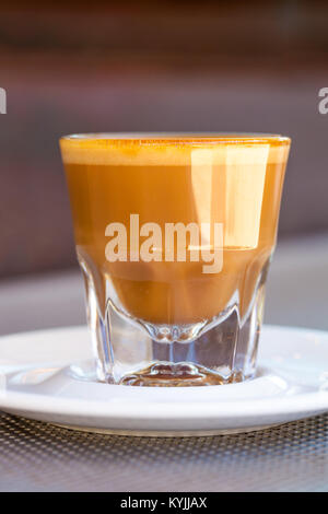 Seitenansicht der Cortado Kaffee in ein kleines Glas Keramik Untertasse auf metallischen Tabelle Stockfoto