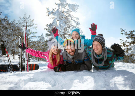 Junge lächelnde Familie Spaß auf Neuschnee im Winterurlaub Stockfoto