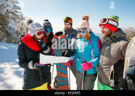Gruppe von Freunden Lesen einer Karte auf Papier in den Winterurlaub im verschneiten Berg Stockfoto
