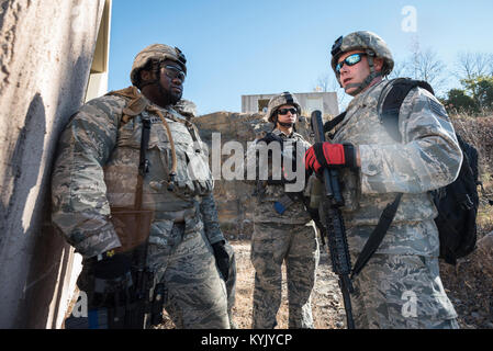 Senior Airman Aaron Harris, Senior Airman Megan Mayes und Tech. Sgt. Gary Coy (von links nach rechts), alle Fire Team Mitglieder von 123. Die Kentucky der Air National Guard Security Forces Squadron, Durchführung von Schulungen einen abgestürzten Piloten innerhalb einer simulierten Afghanischen Dorf in Fort Knox, Ky., Okt. 20, 2015 zu erholen. Die Flieger waren erforderlich, um eine koordinierte Suche auszuführen, während ihre Positionen verteidigen und sich feindliche Kräfte. Stockfoto