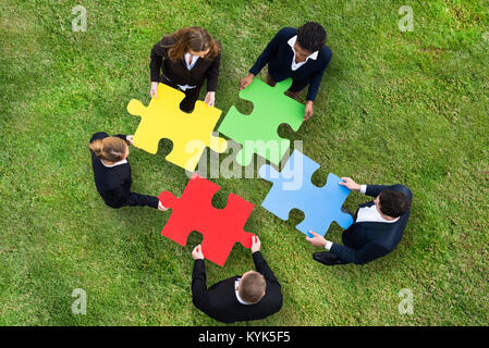 Erhöhten Blick auf die Menschen mit bunten Puzzle auf grünem Gras Stockfoto