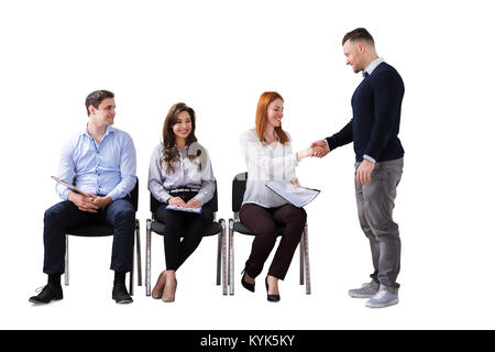 Geschäftsmann Händeschütteln mit Frau neben Menschen warten auf Job Interview Stockfoto