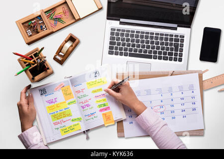 Unternehmer Schreiben Zeitplan im Tagebuch mit Laptop und Handy auf dem Schreibtisch Stockfoto