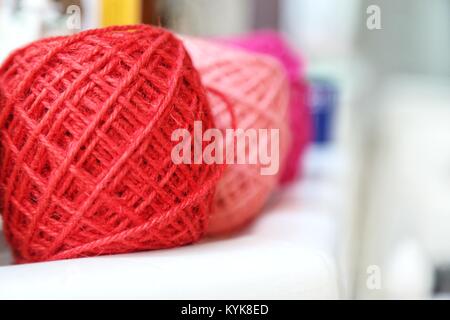 Bunte Strickgarn Kugeln und Nadeln auf weißen Tisch gegen verschwommenen Hintergrund. In der Nähe der bunten Kugeln aus Wolle. Stockfoto