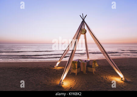 Honeymoon Dinner für Hochzeit paar am Strand in luxuriösen romantisches Hotel, schöner Tisch für zwei bei Sonnenuntergang Stockfoto