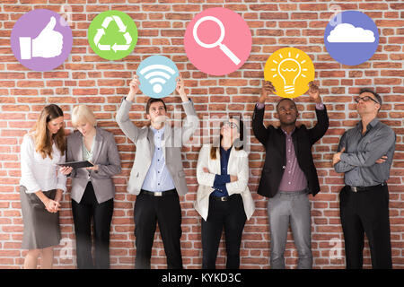 Diverse Geschäftsleute stehen in der Nähe der Mauer Holding Business Symbole Stockfoto