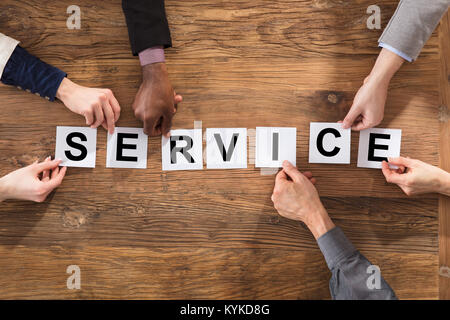 Ansicht von oben aus Geschäftsleuten Hände arrangieren Service Wort auf hölzernen Tisch Stockfoto