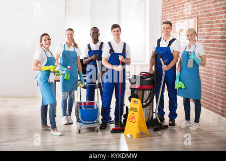 Portrait von Happy Diverse Hausmeister im Büro mit der Reinigung der Geräte Stockfoto