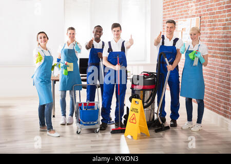 Portrait von Happy Diverse Hausmeister im Büro mit der Reinigung der Geräte mit Daumen nach oben Anmelden Stockfoto