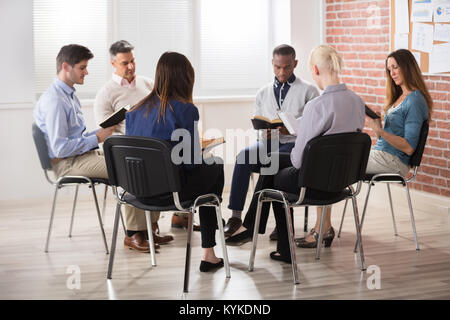 Gruppe von Menschen sitzen auf Stuhl im Kreis lesen Bibeln Stockfoto