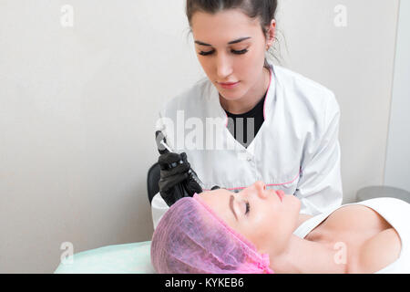 Kosmetikerin führt eine Nadel Mesotherapie Behandlung in das Gesicht einer Frau. Porträt des weiblichen Gesichts erhalten Biorevitalization des Gesichts Prozedur in einer werden. Stockfoto