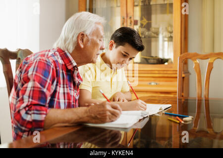 Kleiner Junge macht Schule Hausaufgaben mit alten Menschen zu Hause. Stockfoto