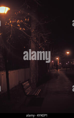 Nacht Szene aus dem City Park, eine einsame alte Herr vorbei am Leuchtturm im Park. Stockfoto