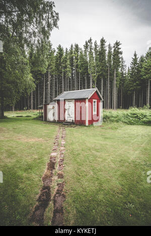 Trail, der bis zu einem kleinen roten Hütte im Wald von hohen Pinien umgeben in Schweden Stockfoto